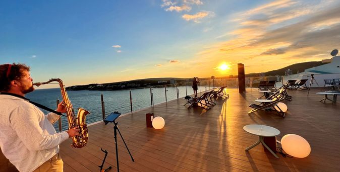 Blick von der Sky Bar auf die Bucht von Magaluf bei Abenddämmerung inkl. Saxophonspieler